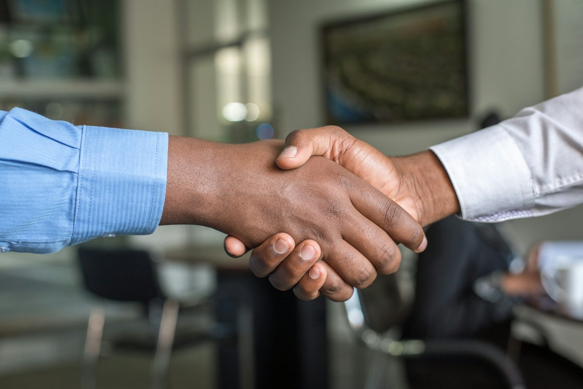 A business handshake between two people in dress shirts.